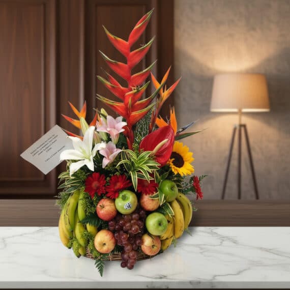 Arreglo floral premium 'Eclipse' con heliconias, lirios, girasoles y frutas frescas como manzanas, uvas y plátanos, sobre una