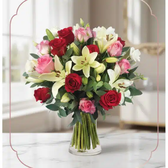 Arreglo floral GIORGIA con rosas rojas, rosas rosadas y lirios blancos en un jarrón de cristal, sobre una mesa de mármol con