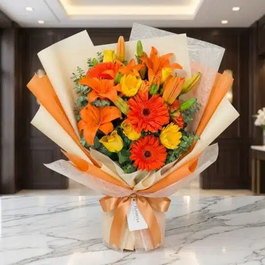 Bouquet LIRICA con lirios naranjas vibrantes, rosas amarillas abiertas y gerberas rojas, envuelto en papel coreano elegante s