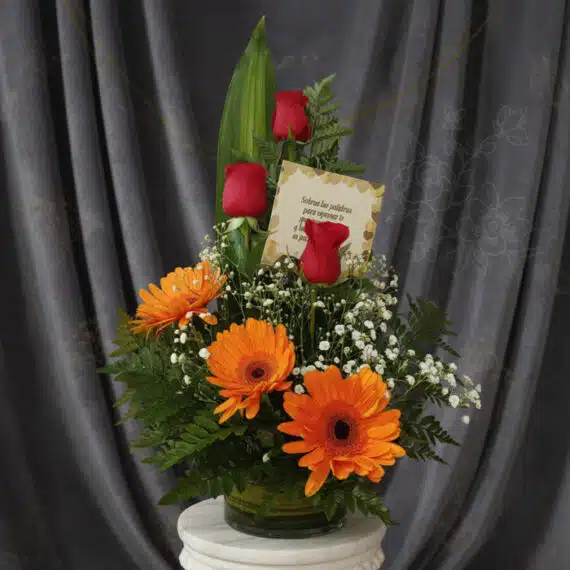 Arreglo floral 'Solitario Tu Recuerdo' con tres rosas rojas, tres gerberas naranjas, follaje verde y flores blancas pequeñas,